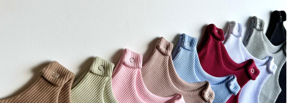 Colorful baby rompers arranged in a row on a white background